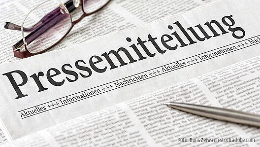Zeitung mit der Überschrift Pressemitteilung mit brille und kuli