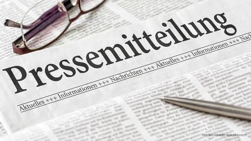 Zeitung mit der Überschrift Pressemitteilung mit Brille und Kuli