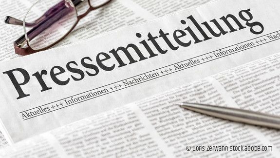 Zeitung mit der Überschrift Pressemitteilung mit Brille und Kuli